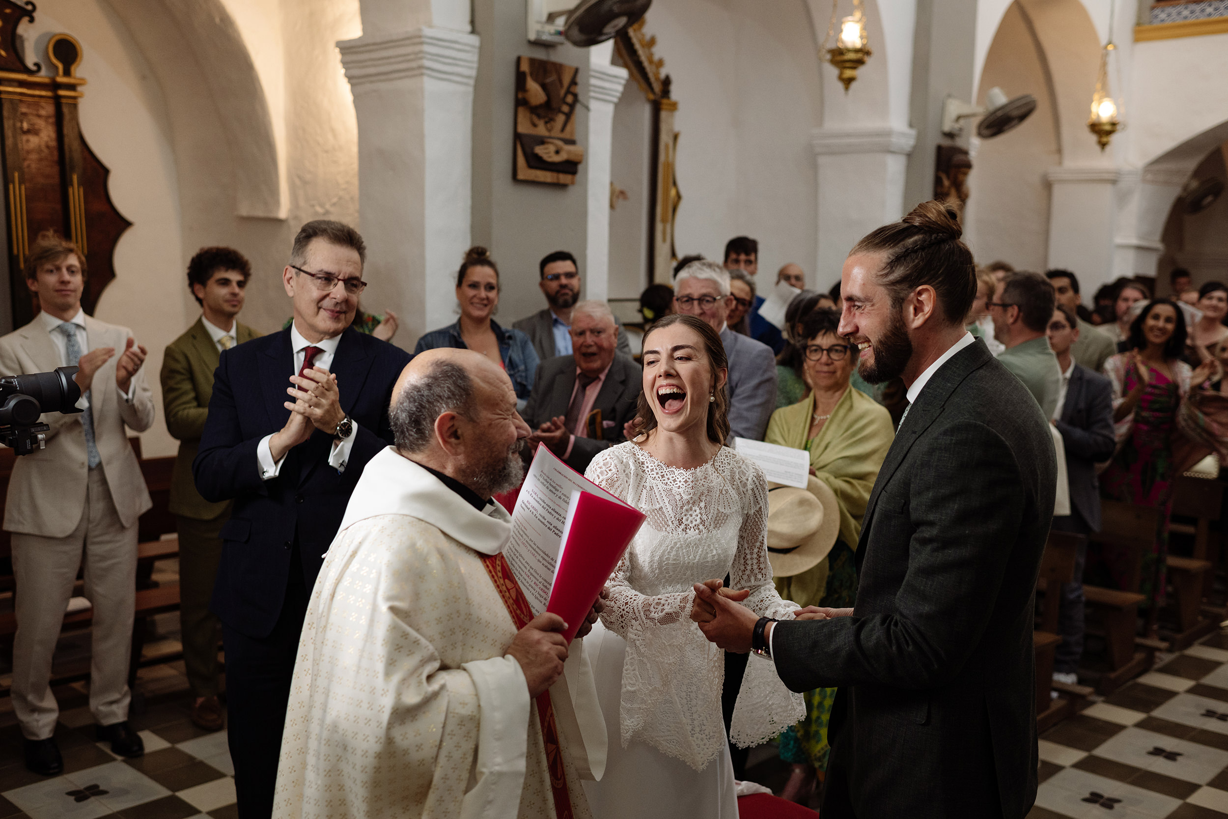 Los novios ríen junto al sacerdote durante la ceremonia